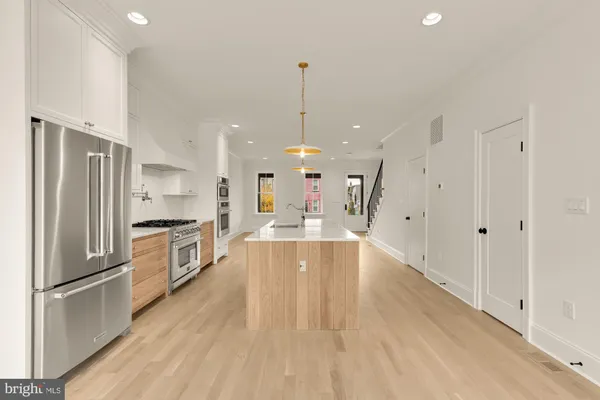 a large kitchen with granite countertop a large counter top a sink stainless steel appliances and cabinets