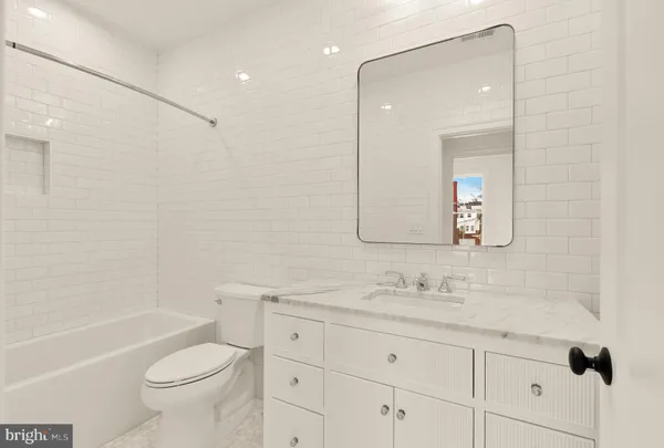 a bathroom with a granite countertop toilet a sink and a bathtub
