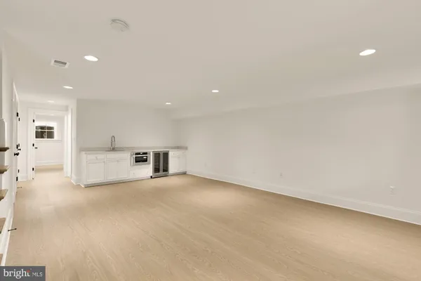 an empty room with kitchen view and a refrigerator