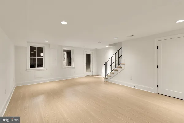 a view of an empty room with wooden floor and windows