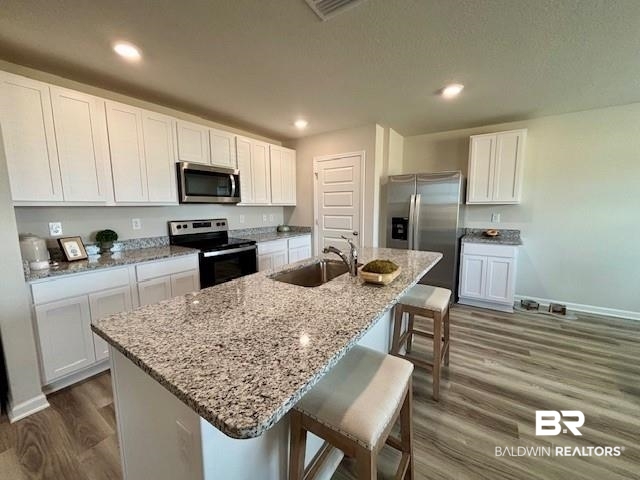22215 Aleutian Avenue Foley, AL 36535 - Photo 5 of 34 Kitchen with appliances with stainless steel finishes, a breakfast bar, a kitchen island with sink, sink, and white cabinets