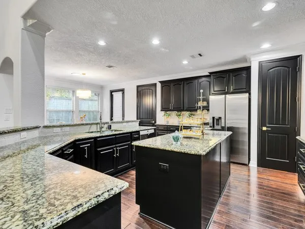 a kitchen with granite countertop kitchen island stainless steel appliances a sink stove and refrigerator