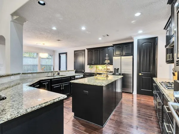 a kitchen with kitchen island granite countertop a sink and stainless steel appliances