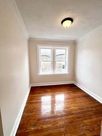 a view of an empty room with window and wooden floor
