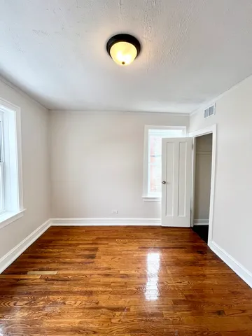 a view of an empty room with wooden floor and window