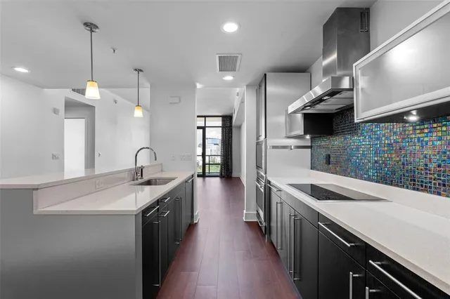 a kitchen with stainless steel appliances granite countertop a sink a stove and a wooden floors