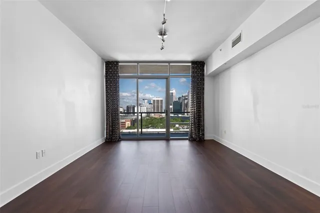 a view of an empty room with wooden floor and a window