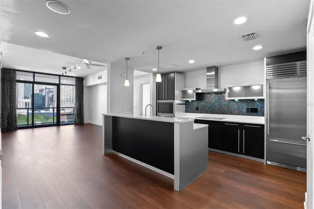 a large kitchen with granite countertop a large counter top stainless steel appliances and wooden floor