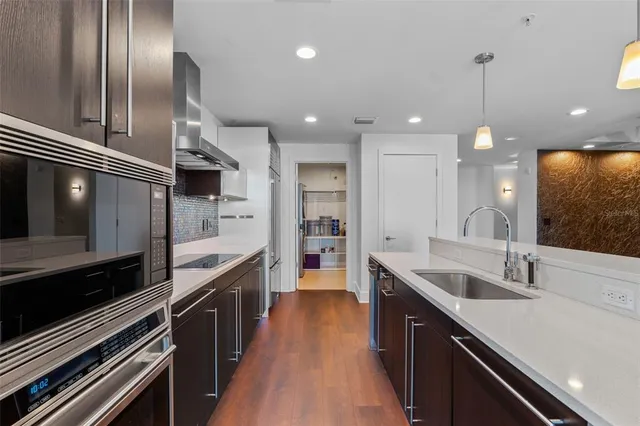a large kitchen with a large counter top space a sink stainless steel appliances and cabinets