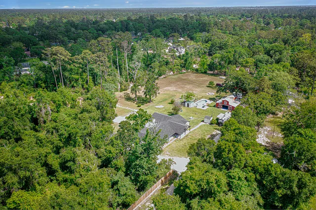 an aerial view of residential house with outdoor space and trees all around