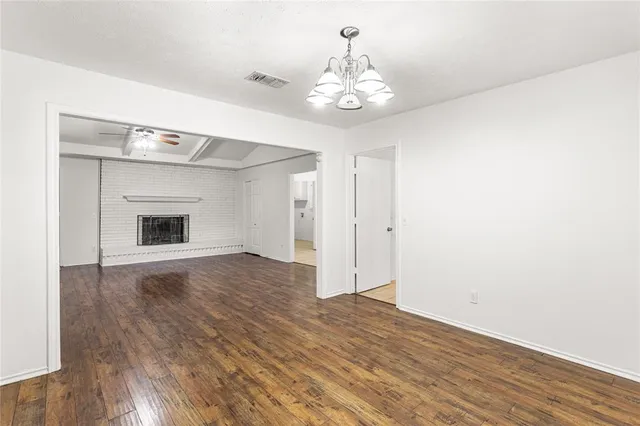 a view of an empty room with wooden floor and chandelier