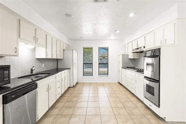 a large kitchen with cabinets a counter top space a sink stainless steel appliances and cabinets