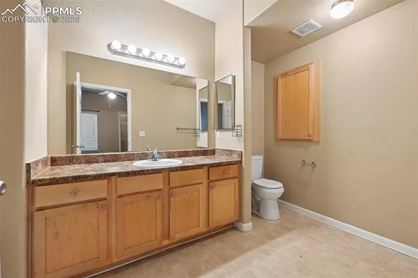 a bathroom with a granite countertop sink a toilet and a mirror