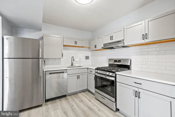 a kitchen with cabinets stainless steel appliances and wooden floor
