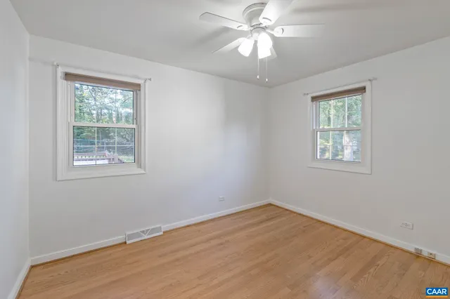 an empty room with wooden floor and fan