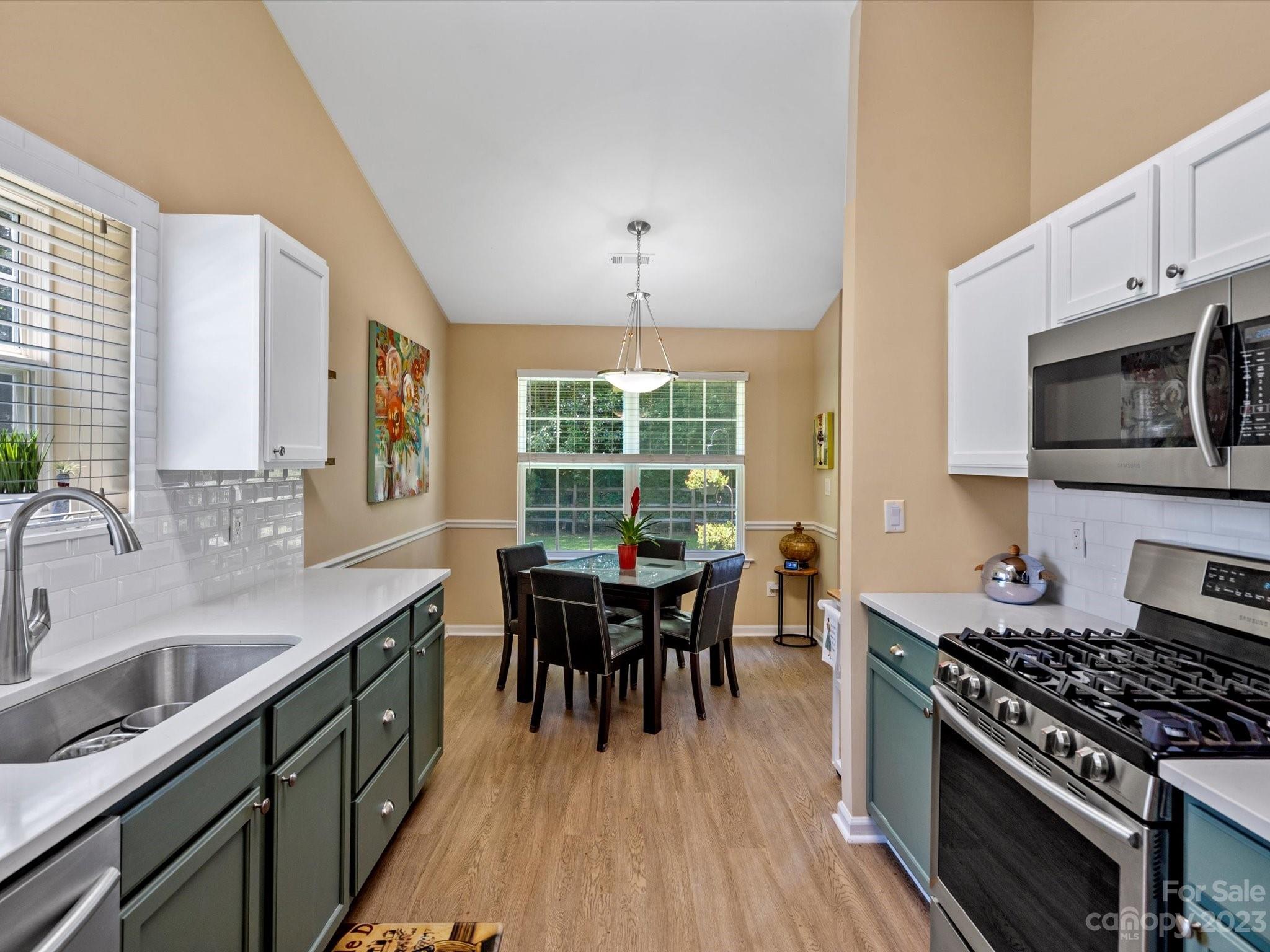 14510 Arbor Ridge Drive Charlotte, NC 28273 - Photo 16 of 34 a kitchen with stainless steel appliances granite countertop a stove a sink dishwasher a microwave oven and a dining table with wooden floor