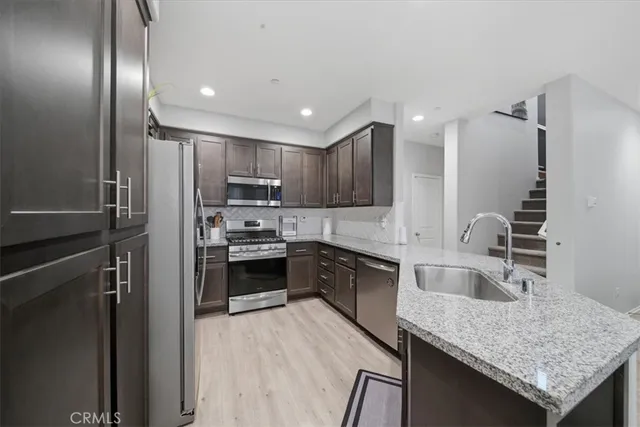 a modern kitchen with granite countertop stainless steel appliances and wooden cabinets