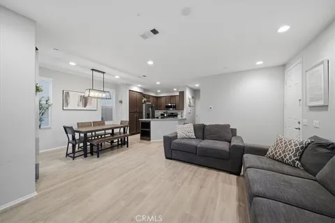 a living room with furniture and a dining table with wooden floor