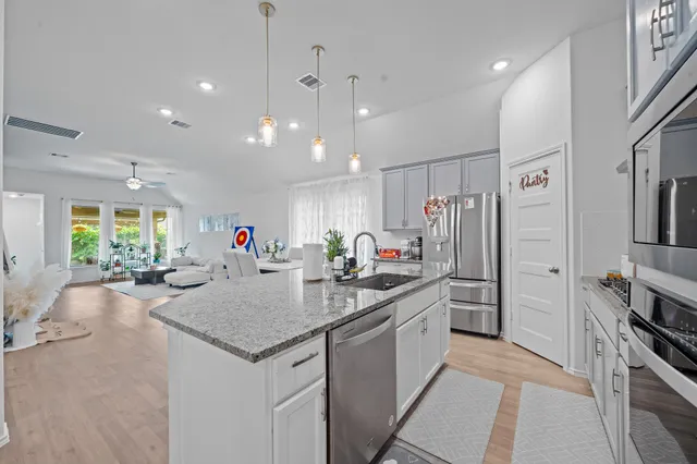 a kitchen with stainless steel appliances granite countertop a stove a refrigerator a sink a dining table and chairs with wooden floor