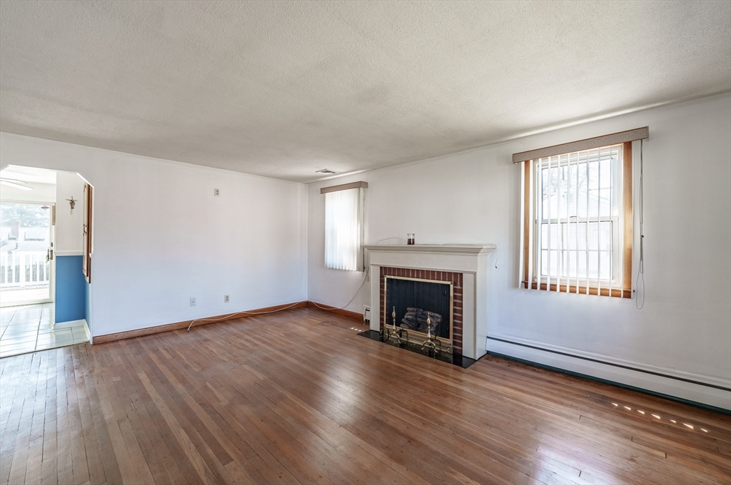 127 Cheyenne Road Springfield, MA 01109 - Photo 8 of 42 an empty room with wooden floor fireplace and windows