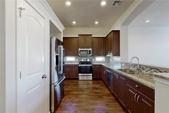 a large kitchen with stainless steel appliances granite countertop a refrigerator stove and oven