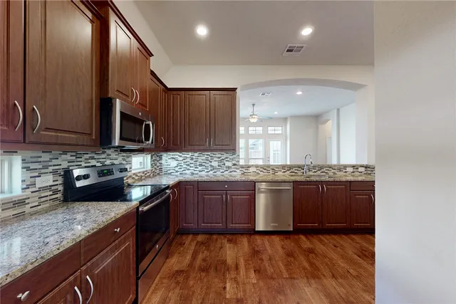 a kitchen with stainless steel appliances granite countertop wooden cabinets a stove top oven a sink and dishwasher