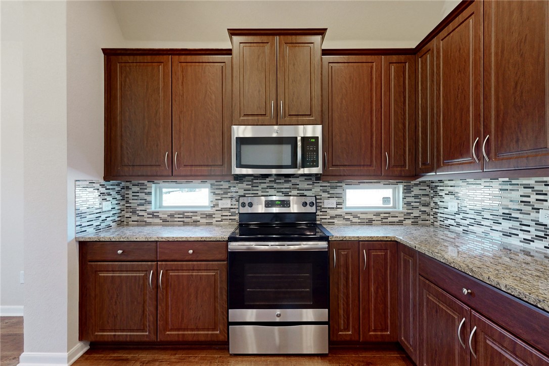 2101 Polmont Drive Bryan, TX 77807 - Photo 10 of 44 a kitchen with granite countertop wood cabinets and stainless steel appliances