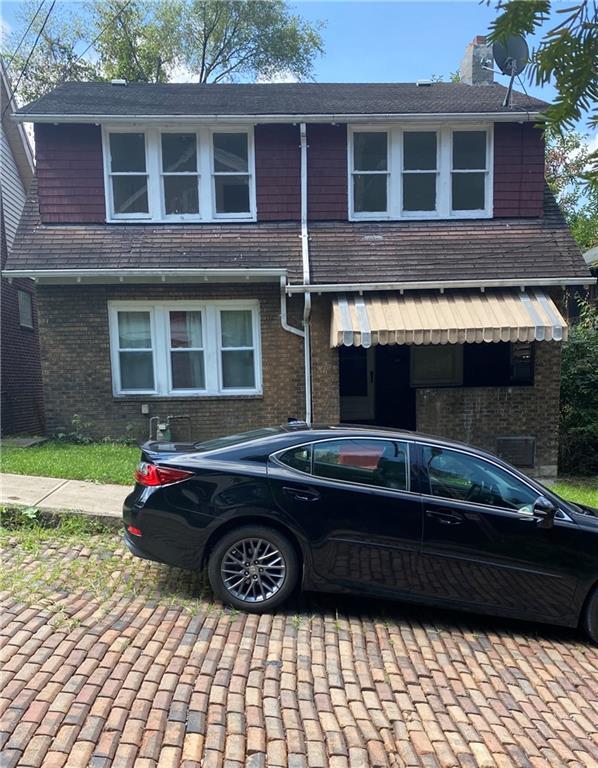 a black car parked in front of a brick house