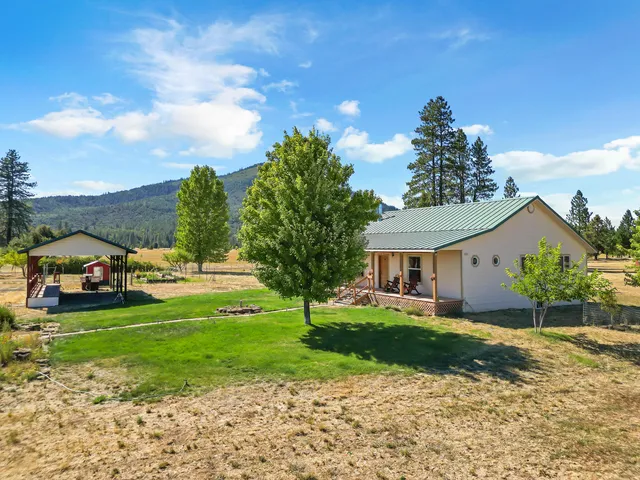 a view of a house with a big yard and large trees