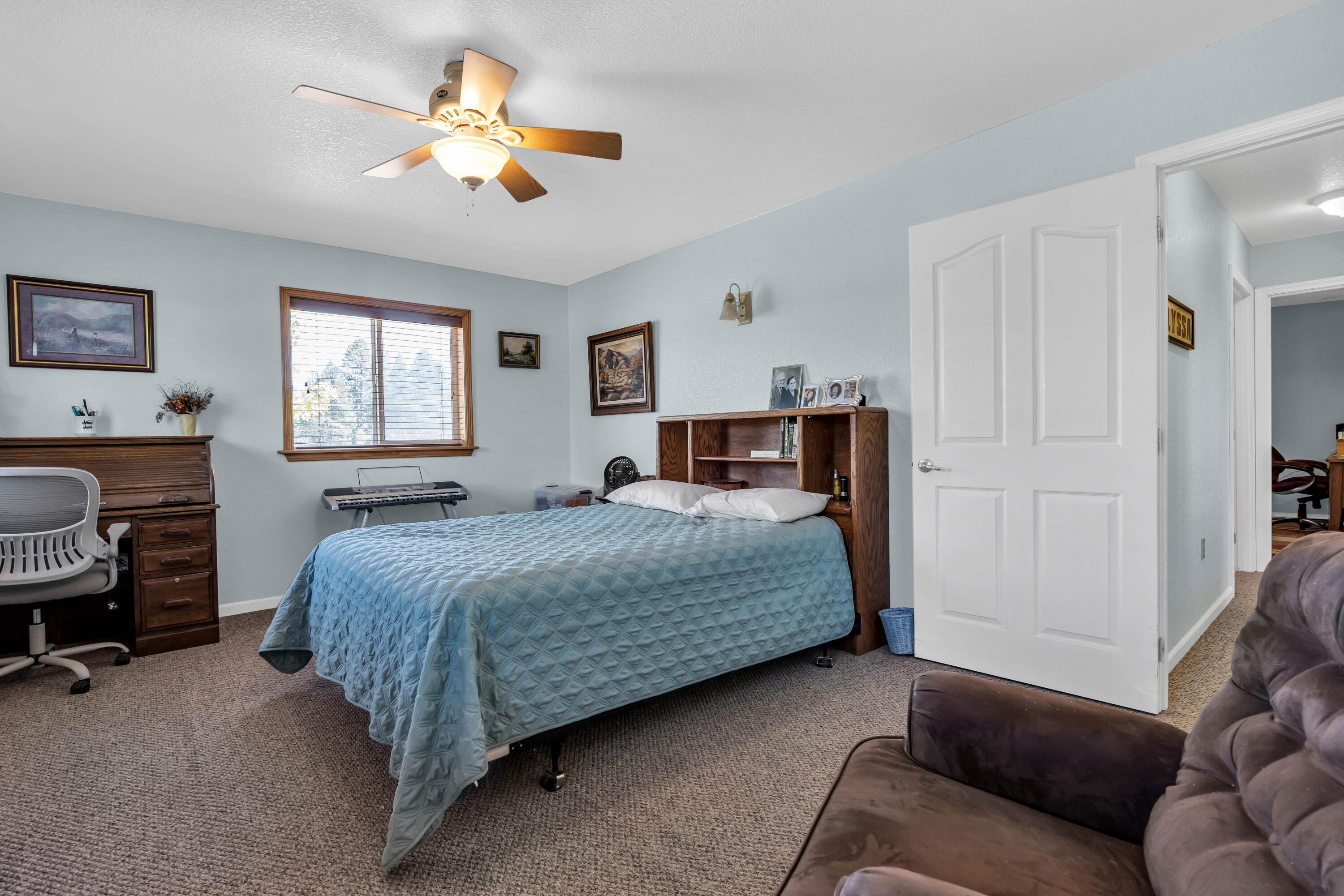26929 Linfield Street Fall River Mills, CA 96028 - Photo 34 of 66 a bedroom with a bed a couch and a chandelier