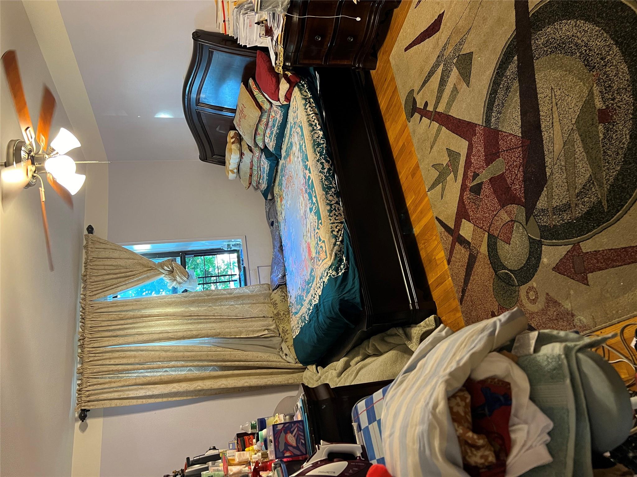 55-30 99th Street, Unit 2H Queens, NY 11368 - Photo 8 of 19 a bedroom with a bed and a chandelier