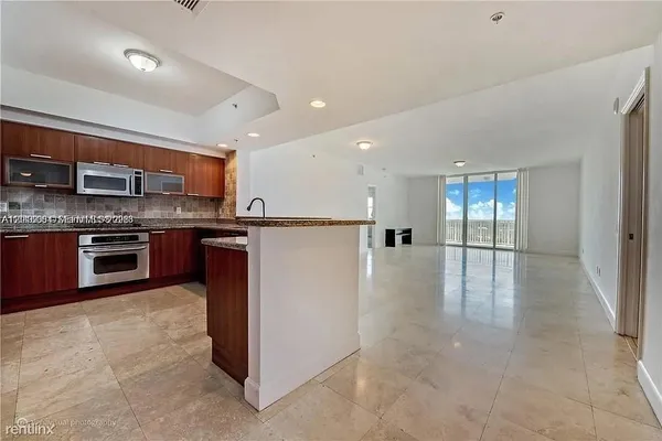 a kitchen with stainless steel appliances granite countertop a stove top oven a sink and a refrigerator