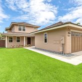 a view of a house with a yard plants and large tree