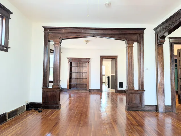 a view of empty room with wooden floor and fan