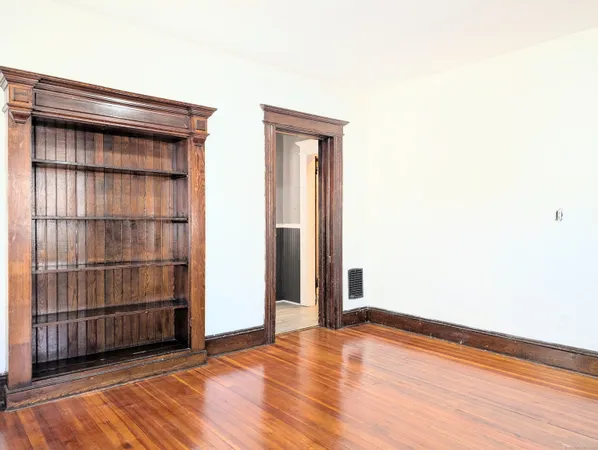 an empty room with wooden floor and cabinet