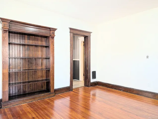 an empty room with wooden floor and cabinet