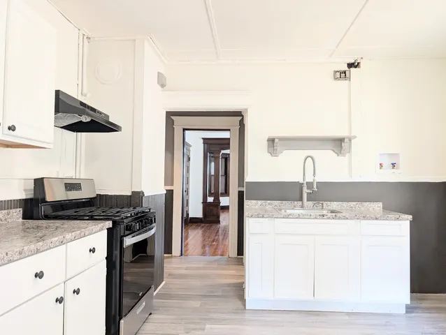 a kitchen with stainless steel appliances granite countertop a sink a stove and a wooden floors