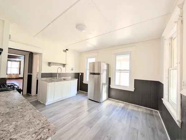a kitchen with a refrigerator and wooden floor