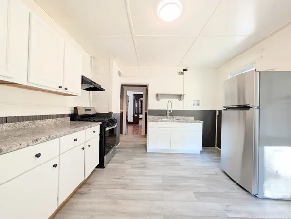 a large kitchen with stainless steel appliances and white cabinets