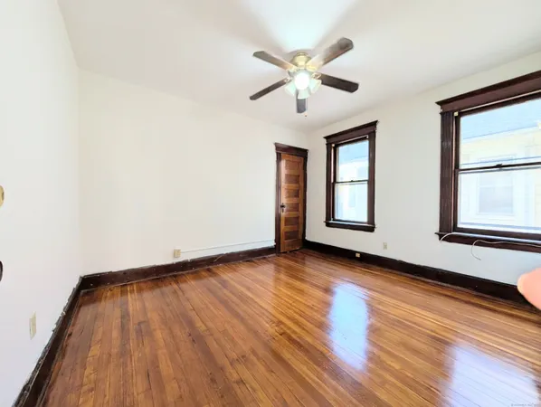 a view of an empty room with wooden floor and window