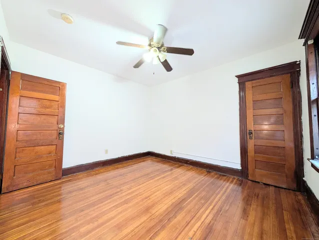 an empty room with wooden floor closet chandelier fan and windows