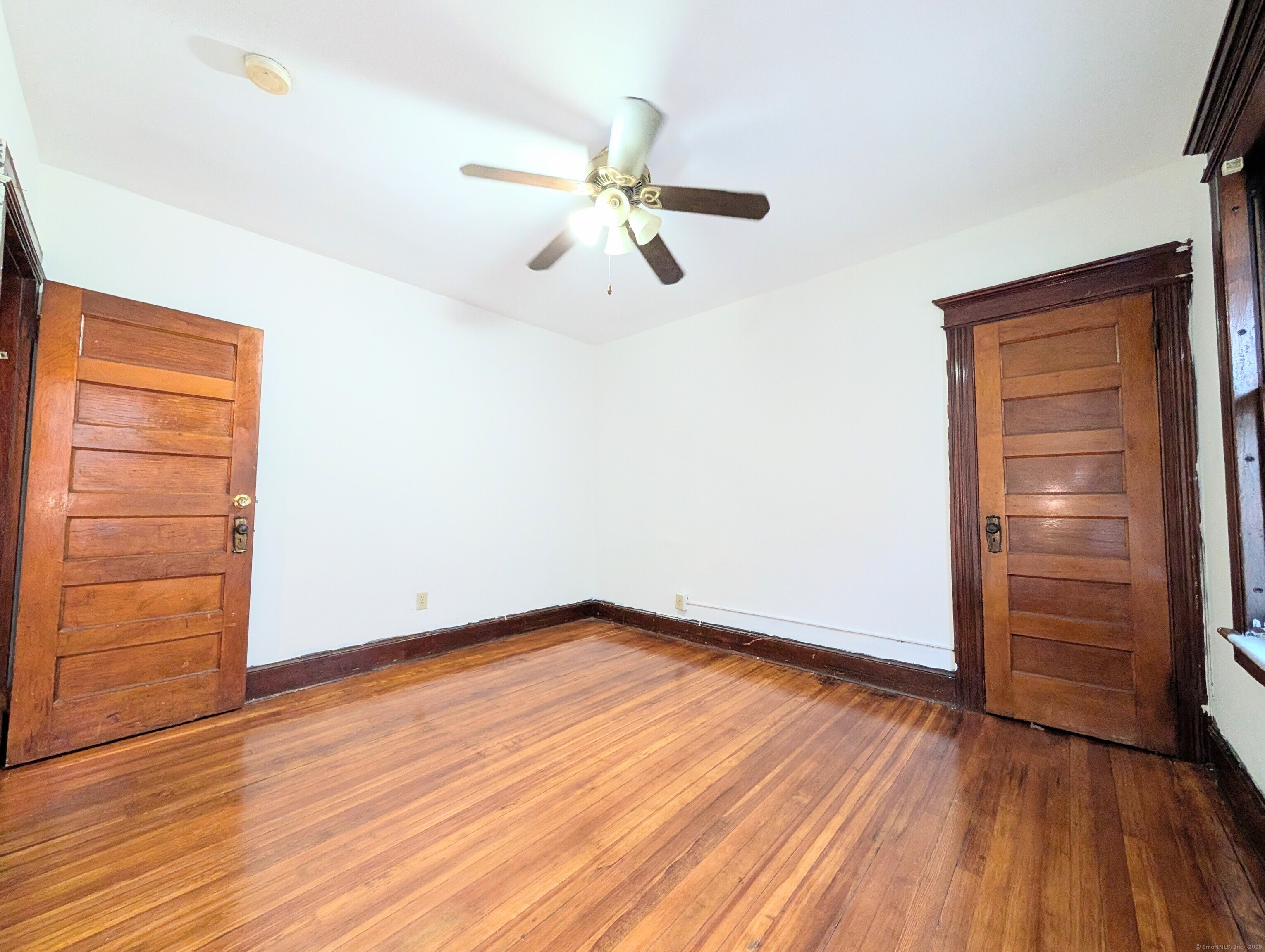 133 Poplar Street Bridgeport, CT 06605 - Photo 35 of 36 an empty room with wooden floor closet chandelier fan and windows