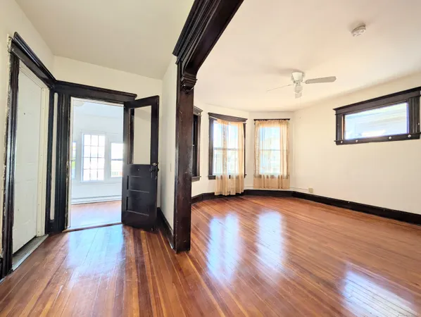 a view of a big room with wooden floor and windows