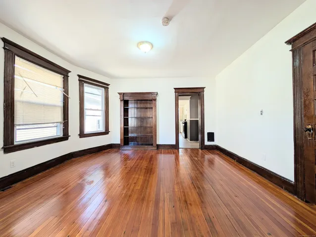 a view of an empty room with window and wooden floor