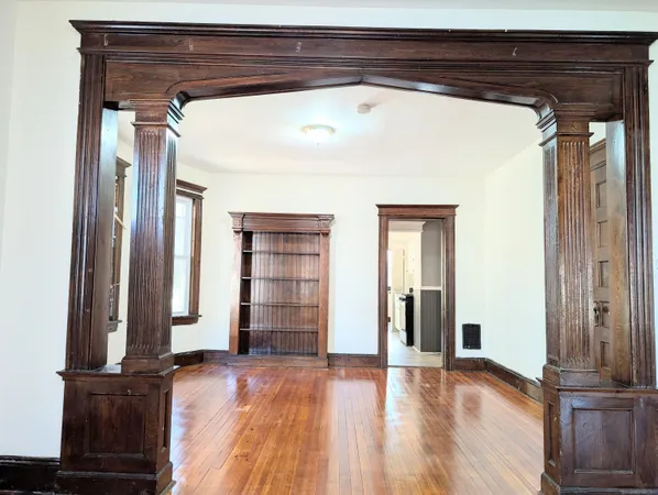 a view of empty room with wooden floor and wall