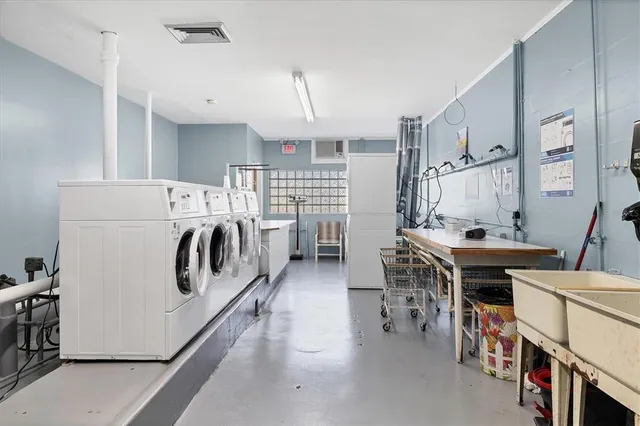 a kitchen with stainless steel appliances a white stove top oven a sink dishwasher and a dining table with white cabinets