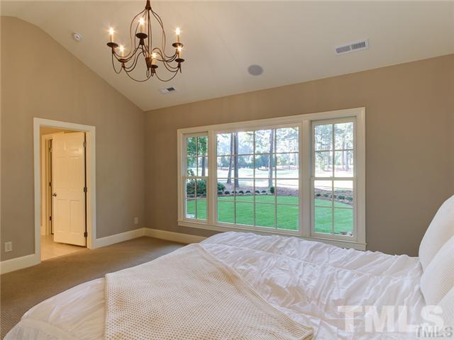 7003 North Ridge Drive Raleigh, NC 27615 - Photo 17 of 25 a bedroom with a large bed and a chandelier