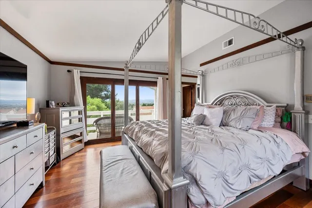 a bedroom with a large bed and a flat tv screen on dresser