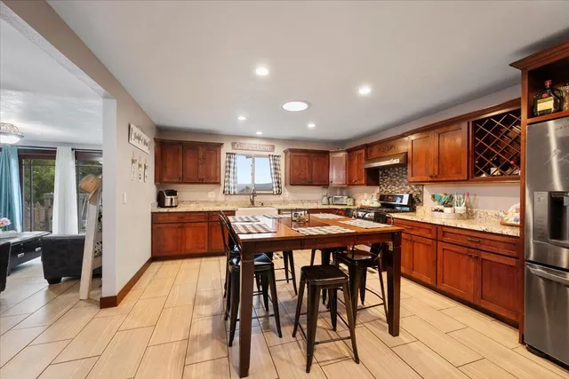 a kitchen with stainless steel appliances granite countertop table chairs sink refrigerator and cabinets