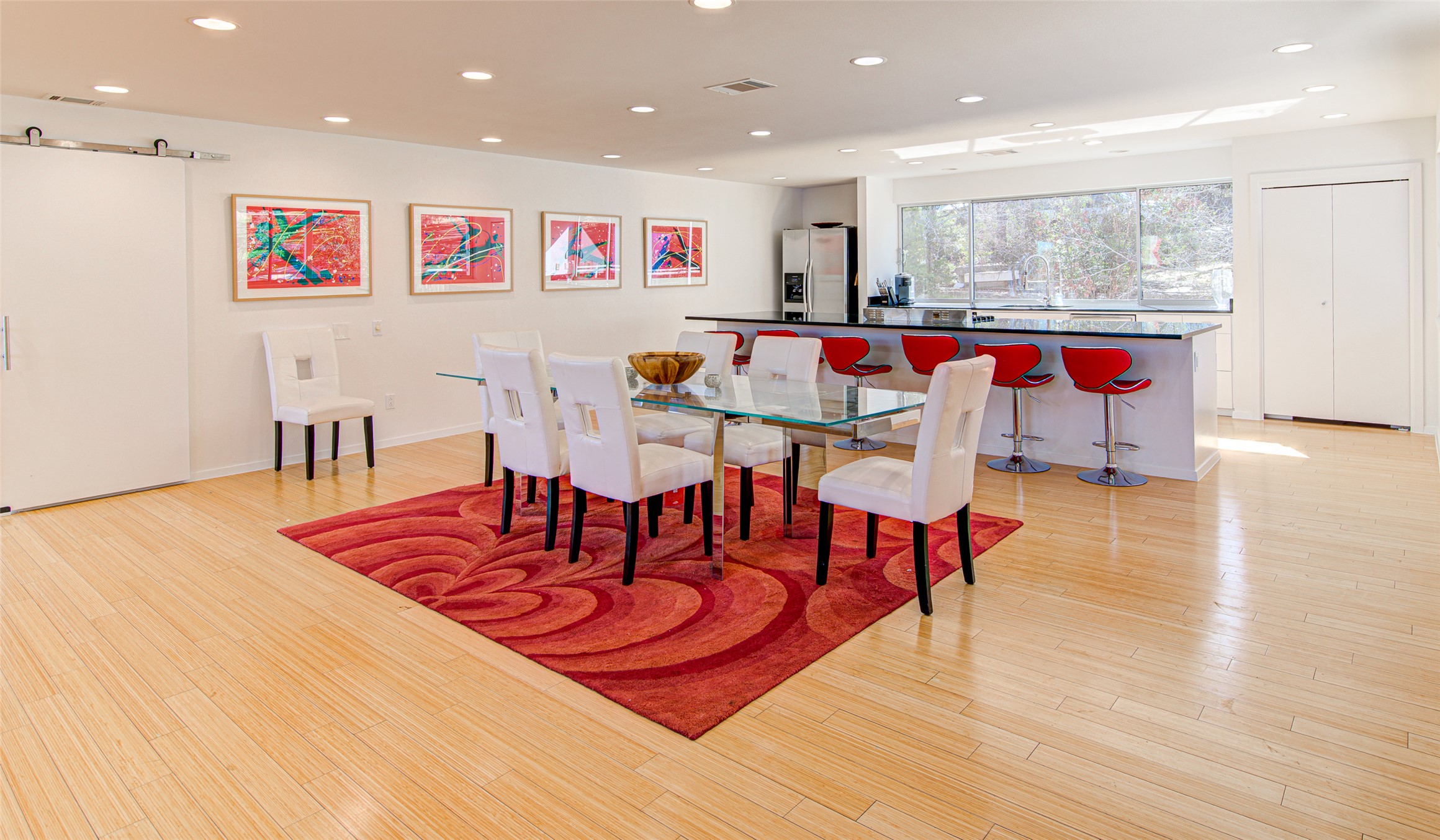 9707 Timber Ridge Pass Austin, TX 78733 - Photo 5 of 18 Warm wood flooring stretches across an expansive open layout connecting the dining area to the kitchen.